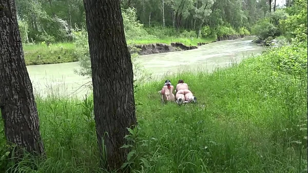 Voyeur outdoors peeps at two naked lesbians. Nudists with big asses sunbathe and enjoy nature and masturbation.